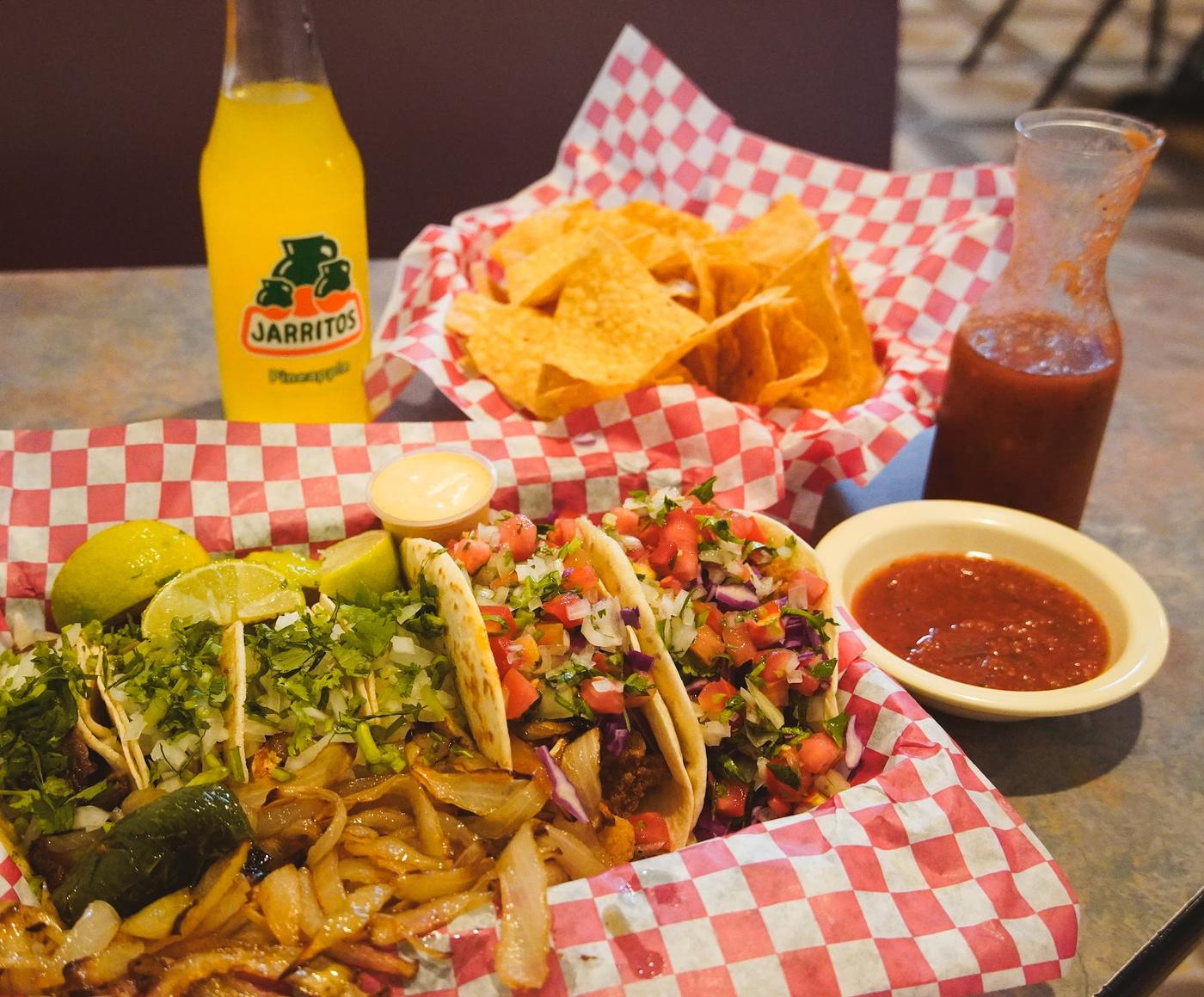 Tacos, tortilla chips and red salsa on checkered paper